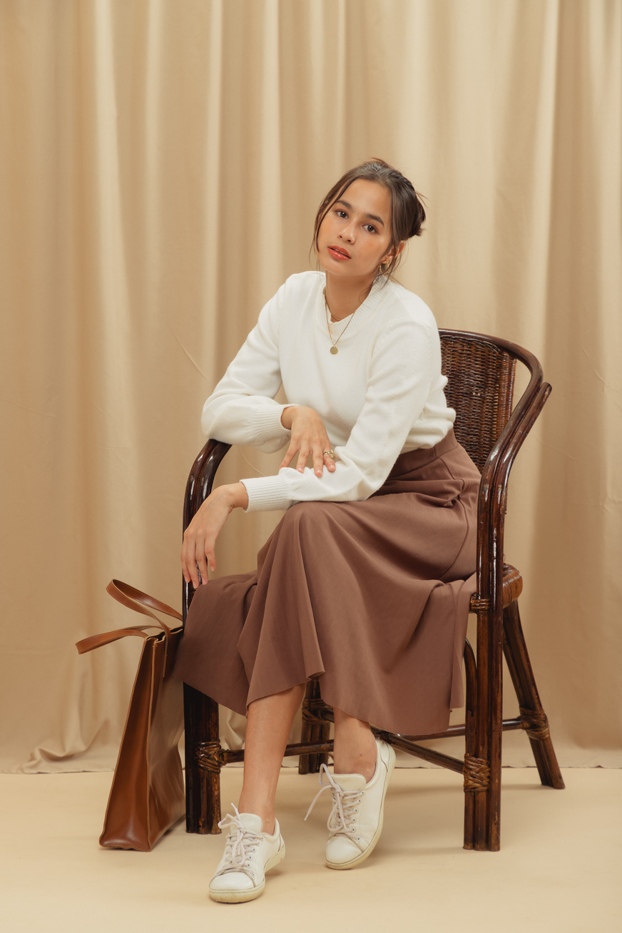 Woman in White Sweater and Brown Skirt on Beige Background
